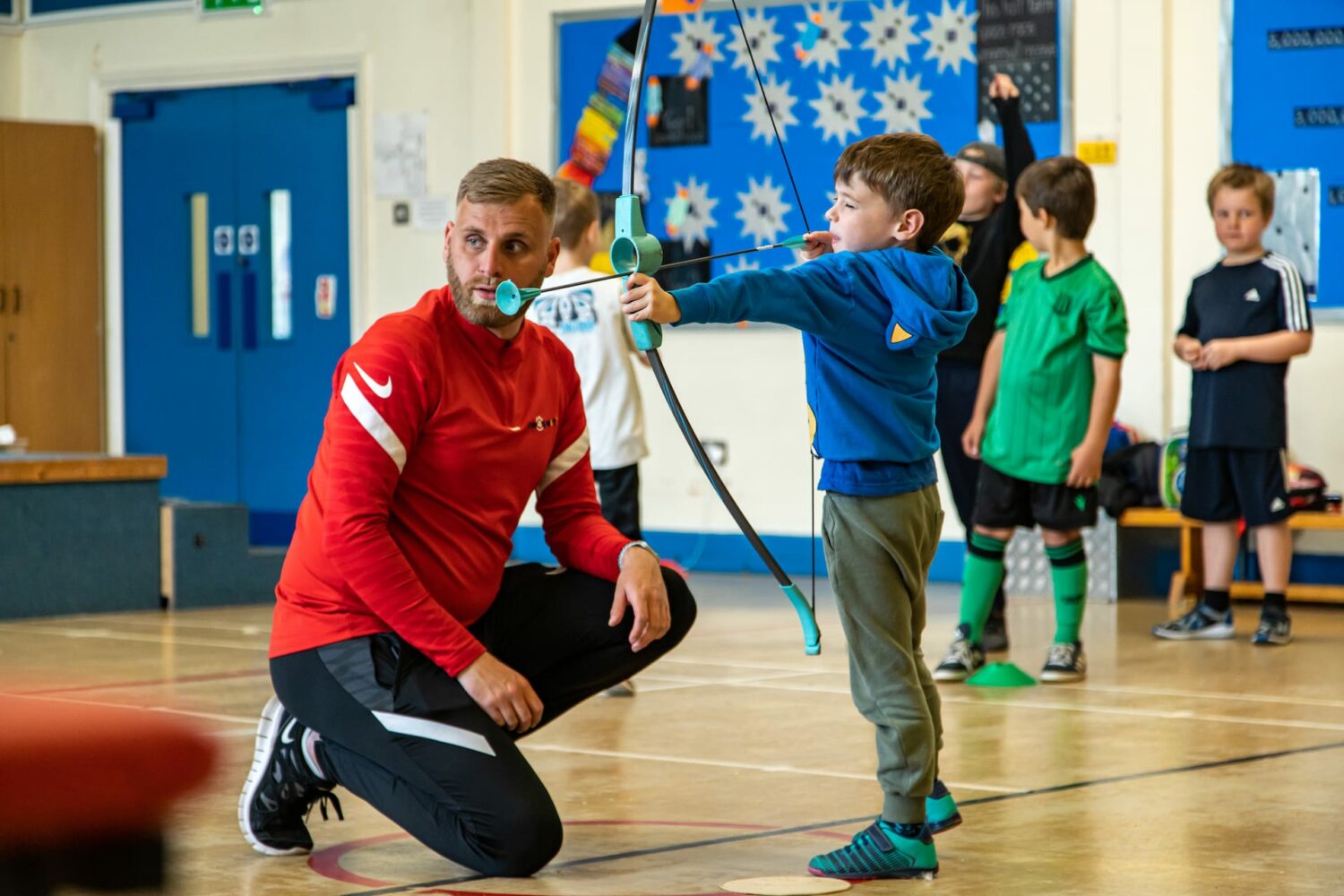 time4sport educator with child holding bow and arrow for Archery