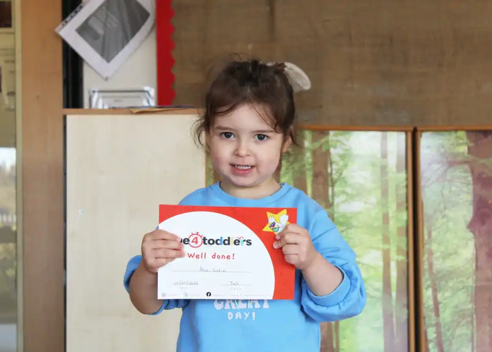 child holding time4toddlers certificate